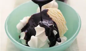 En skopa vaniljglass med vispgrädde och mörk chokladsås som hälls över. Perfekt för ett enkelt chokladsås recept.