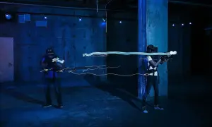 Två personer spelar VR-spel med ljusgevär i en mörk lokal. Perfekt för inomhusaktiviteter i Stockholm.