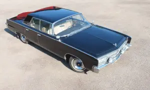 Svart imperial bil med kromdetaljer och ljus interiör, parkerad på grus. En klassiker som väcker beundran.