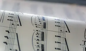 Zrolowana partytura muzyczna, nuty tworzą ambientową atmosferę.