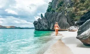 Frau genießt das türkisfarbene Wasser und den weißen Sandstrand auf den Philippinen. Ein perfekter Ort für Backpacking-Abenteuer.