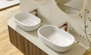 Due lavabi ovali bianchi su un mobile bagno su misura con finitura a listelli verticali. Rubinetteria color rame.