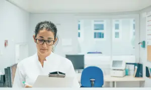 Optyk w okularach notuje coś na kartce, zastanawiając się, ile zarabia optyk okulista.