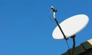 Biała antena satelitarna na dachu, gotowa do ustawienia. Dowiedz się, jak ustawić antenę satelitarną, by cieszyć się najlepszym sygnałem.
