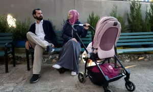 En man och en kvinna, som representerar muslimer i Sverige, sitter på en bänk med en barnvagn.