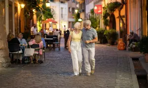 Ein älteres Paar spaziert abends durch eine Gasse in Freiburg. Was kann man in Freiburg machen? Hier: gemütlich essen gehen und die Atmosphäre genießen.