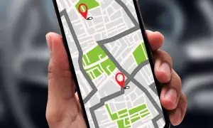 Dłoń trzyma smartfon z mapą i pinezkami. Dowiedz się, jak namierzyć telefon po numerze, by zawsze wiedzieć, gdzie jest bliska osoba.