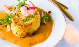 Un délicieux soufflé de crabe, nappé d'une bisque onctueuse et garni de crevettes et de roquette.