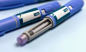 Dwa niebieskie peny z zielonymi etykietami z napisem "1 mg" i widocznym wkładem.