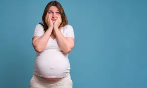 Donna incinta con le mani sul viso, sguardo preoccupato. Piangere in gravidanza fa male, meglio cercare supporto.