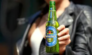Mano che tiene una bottiglia di Heineken 0.0, la birra senza glutine, rinfrescante e gustosa.