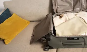 Koffer packen für den Urlaub. Kleidung wird sorgfältig in den Koffer gelegt, bereit für die Reise.