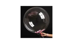 Przezroczysty bubble balon z różowymi płatkami kwiatów w środku i na dole, trzymany przez dłoń.