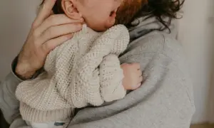 En pappa tröstar sitt ledsna barn som verkar ha bebis hård i magen.