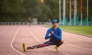 Kobieta w sportowym stroju rozciąga się na bieżni. Prawidłowe oddychanie podczas biegu jest kluczowe dla wydajności.