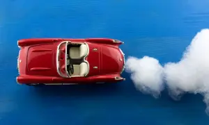 Rotes Spielzeugauto mit 07-Kennzeichen fährt auf blauem Untergrund, Rauch steigt auf. Wer darf fahren?