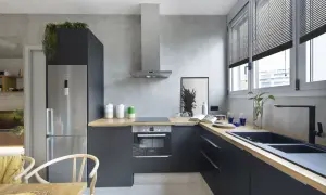 Cocina moderna con paredes de microcemento, muebles oscuros, encimera de madera y electrodomésticos de acero inoxidable.