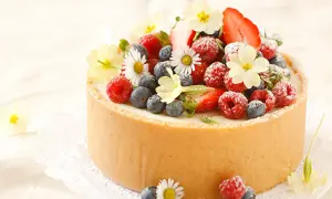 Torte mit frischen Beeren und Blumen dekoriert.