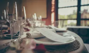 Mesa elegante con copas, cubiertos y menú. ¿Cuántas estrellas Michelin se pueden tener en una cena así?