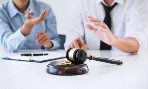 Sądowy młotek i obrączki na stole, symbolizujące umowę podziału majątku wspólnego.