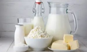 Mleko, twaróg, masło i śmietana na drewnianym tle. Zastanawiasz się, ile kalorii ma mleko?