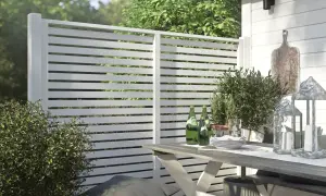 En vit spaljé som kan användas för att bygga vindskydd. Ett utemöblemang med bord, stolar och dekorationer.