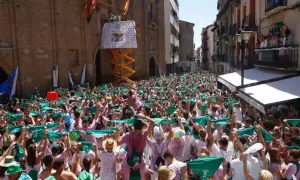Multitud celebra el programa fiestas Huesca, agitando pañuelos verdes. Un cartel anuncia "25".