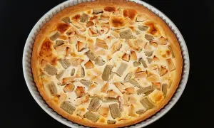 Tarte rhubarbe pomme dorée, garnie de morceaux de fruits et d'une crème onctueuse, prête à être dégustée.