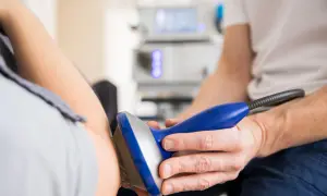Fysioterapeut behandlar armen med ultraljudsapparat för att lindra musarm symtom.