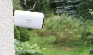 Kamera Eufy Security zapewnia monitoring działki przez internet mobilny. Widok ogrodu z kamerą zamontowaną na ścianie.
