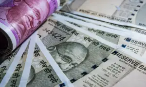 Stos banknotów, w tym fioletowy 2000 rupii i szare 500 rupii, z wizerunkiem Mahatmy Gandhiego. Waluta Indii.