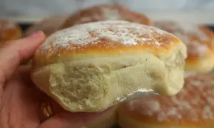 En hand håller en nybakad tekaka, pudrad med mjöl. Perfekt för ett enkelt tekakor recept.