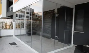 Veranda balcone con vetrate scorrevoli, luci decorative e piante. Spazio moderno e luminoso.