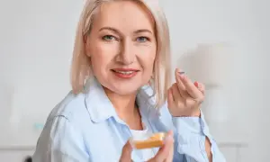 Kobieta trzyma soczewkę kontaktową na palcu i pojemniczek z soczewkami.