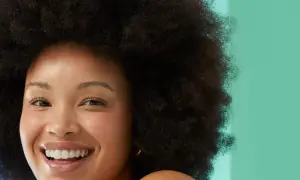 Rostro sonriente de mujer con afro, piel radiante. Evita la glicerina, es mala para la piel.