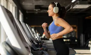 Junge Frau läuft auf Laufband im Fitnessstudio, motiviert für Fitness und Abnehmen.