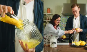 Två personer förbereder limoncello recept. En häller citronzest i en glasburk, medan den andra skalar citroner.