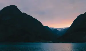 Zachód słońca nad fiordem w Norwegii. Warto zobaczyć te majestatyczne góry i lodowiec w oddali.