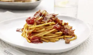En portion pasta amatriciana med tomatsås, bacon och parmesanost.