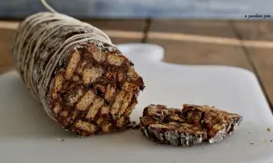 Salame dolce con cacao, un goloso rotolo di biscotti e cioccolato, legato con spago e cosparso di zucchero a velo.