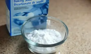 Pudełko sody oczyszczonej i miseczka z białym proszkiem. Soda oczyszczona na swędzenie skóry to domowy sposób na ulgę.