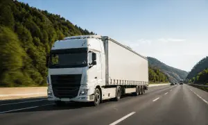 Un camion blanc roule sur une autoroute bordée d'arbres. Le conducteur utilise un chronotachygraphe numérique pour enregistrer son trajet.