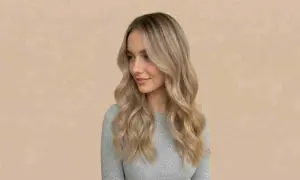 Kobieta z falowanymi włosami w odcieniu piaskowy blond, z subtelnymi refleksami.