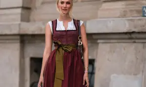 Frau mit Dirndl und einer grünen Schürze, die sie elegant um die Taille gebunden hat.
