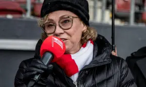 Prezes Cracovii w czapce i szaliku klubu, z mikrofonem w ręku, przemawia do zgromadzonych.