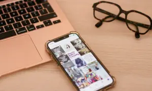 Telefon z uszkodzonym ekranem obok laptopa i okularów. Szukasz sposobu, jak wyświetlić uszkodzony ekran telefonu na komputerze?