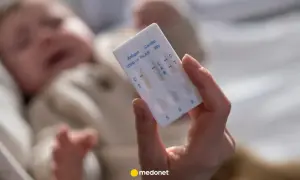 Dłoń trzyma test combo na COVID-19, grypę i RSV. W tle niewyraźne dziecko, być może z objawami RSV.