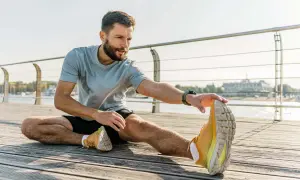 Mann dehnt sich am Wasser. Er fragt sich, wie lange Dehnung halten für optimale Ergebnisse.