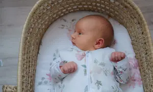 Malutkie dziecko w śpiworku z motywem kwiatowym leży w wiklinowym koszu. Czy to sids? Nie, to po prostu słodki bobas.