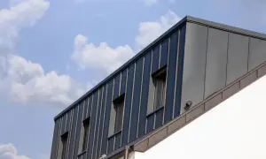 Moderne Dachgaube mit stehenden Blechbahnen und Fenstern. Informieren Sie sich über Dachgaube Kosten für Ihr Bauprojekt.